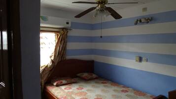 A bedroom with a bed, a ceiling fan, and a window with curtains.
