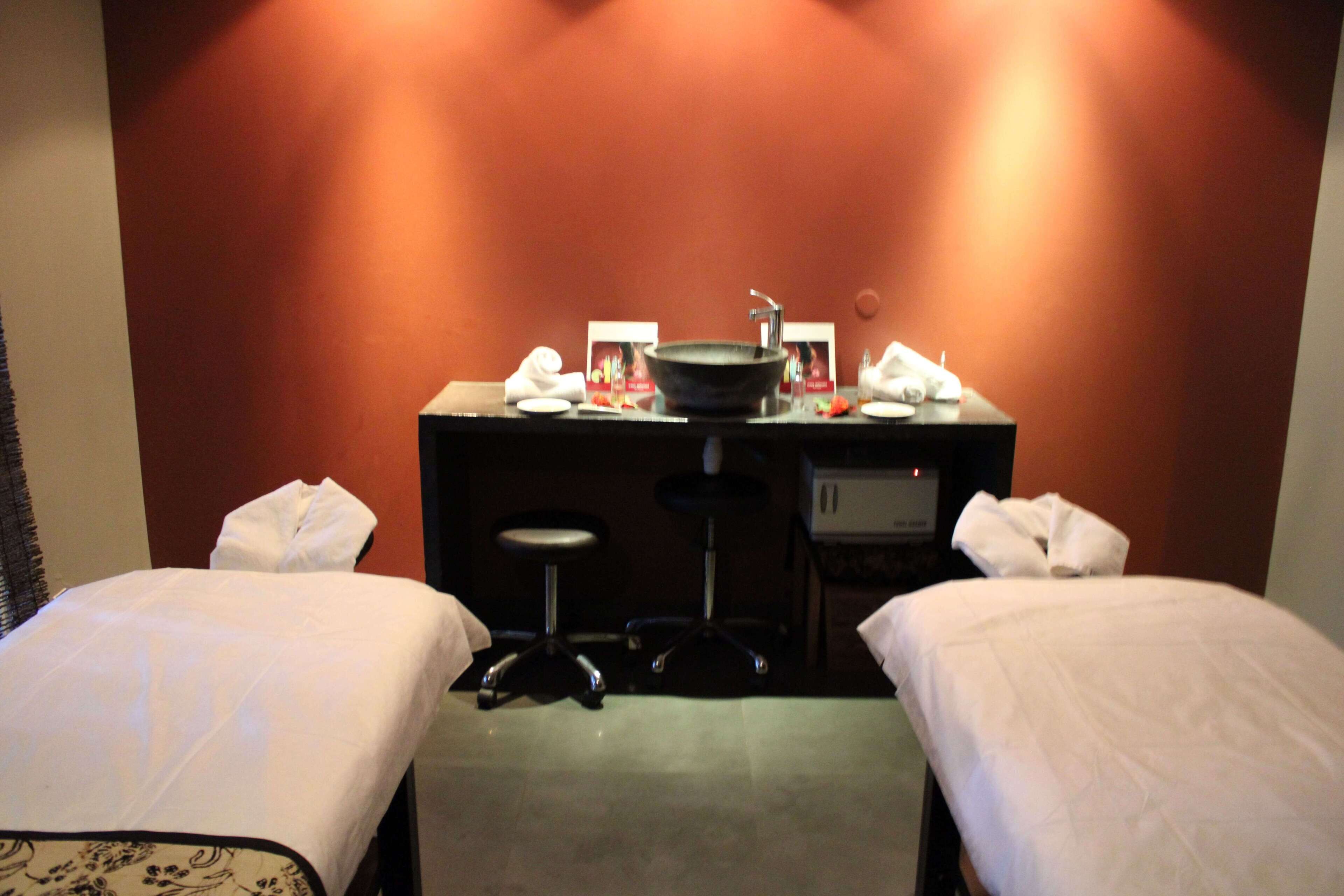 A hotel room with two beds, a desk with a sink, and a chair.