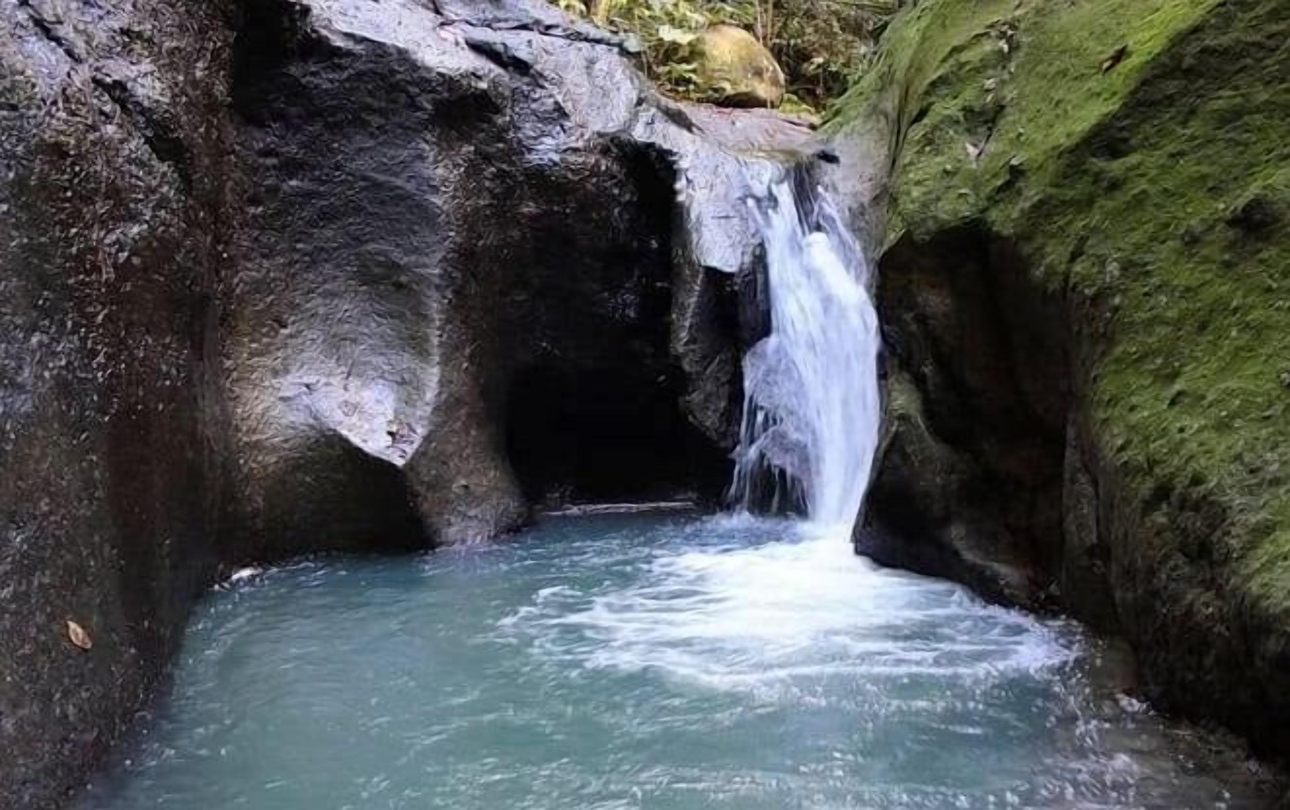 Une cascade se déversant dans un canyon rocheux, où l’eau claire alimente un bassin situé en contrebas.