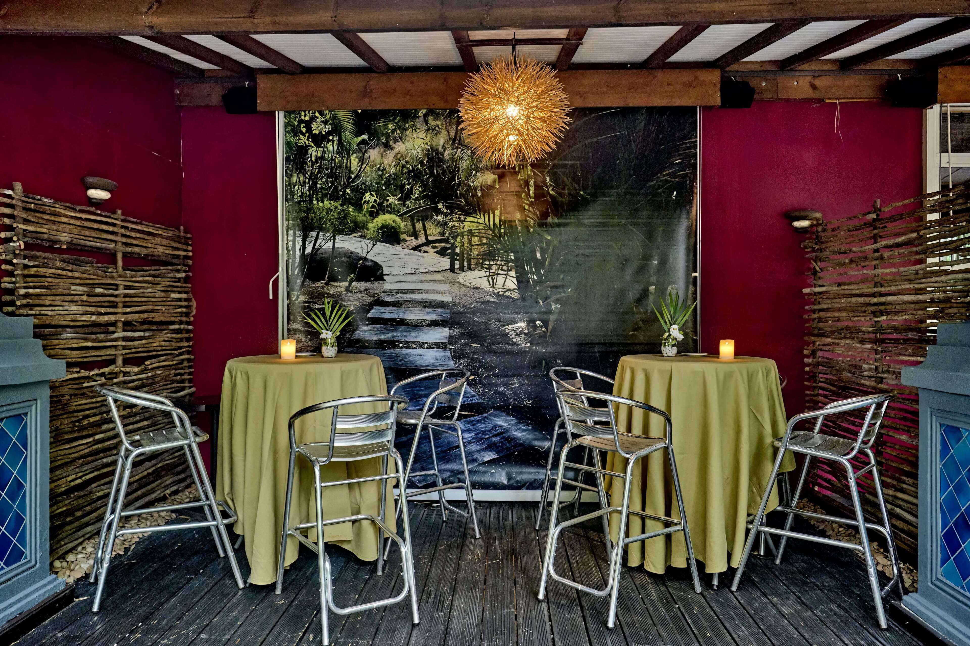 Un comedor con un mural de una cascada, dos mesas con sillas y una lámpara colgante.