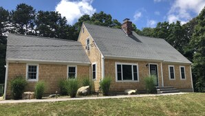 A two-story house with a sloped roof, brick exterior, and a chimney.