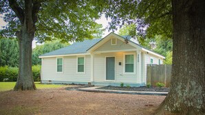 A single-story house with a gabled roof, a front porch, and a wooden fence.