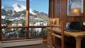 A cabin with a wooden desk, a laptop, and a view of snow-covered mountains. - SPECTACULAR VIEW of Big Sky-Hot Tub & Fireplace-1/2 Mile on Free Shuttle to Mtn. (Big Sky)