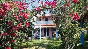 A two-story building with a balcony, surrounded by lush greenery and flowering plants. - House in Cumuruxatiba prox. Cliffs, mezzanine and spacious suite, sea view  (Prado)