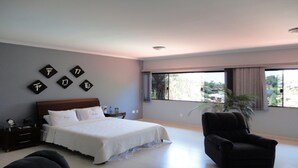A bedroom with a bed, a chair, a nightstand, and a window with a view of greenery. - House in a gated community, 45 minutes from São Paulo. (ITATIBA)