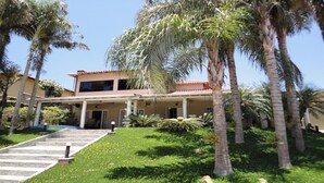 A two-story house with a covered porch, palm trees, and a well-maintained lawn. - House in a gated community, 45 minutes from São Paulo. (ITATIBA)