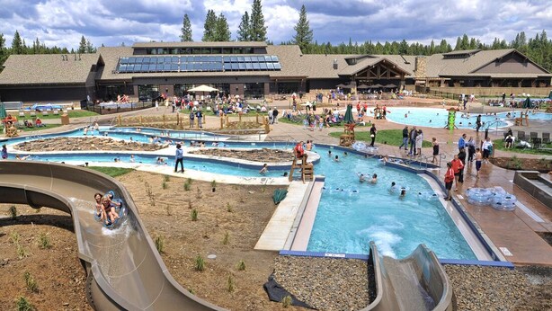 A water park with multiple pools, slides, and a large building with solar panels in the background. - Large Luxury Family Home (Sunriver)