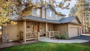 A two-story house with a front porch, a garage, and a stone foundation. - Large Luxury Family Home (Sunriver)