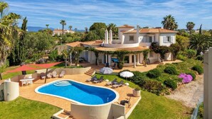 Une villa avec piscine, espace salon extérieur et jardin.