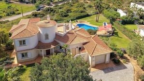 Une grande maison avec une piscine, entourée d’une végétation luxuriante et offrant une vue sur la mer.
