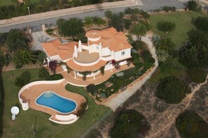 An aerial view of a large house with a swimming pool, surrounded by landscaped gardens and palm trees. - Family‑Friendly Villa with Beautiful Sea Views, Private Pool & Spacious Gardens (Estômbar)