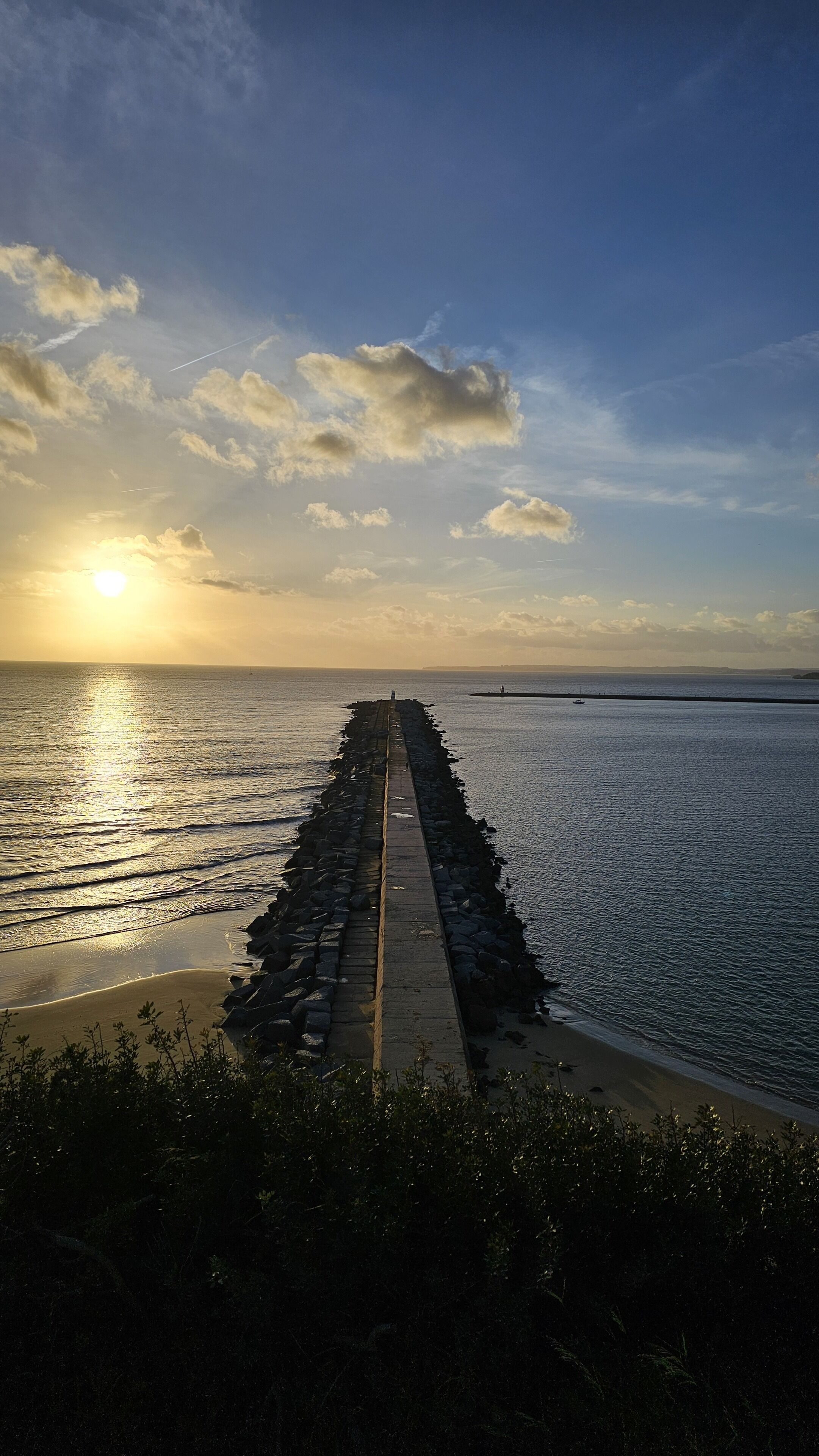 A pier extending into calm waters with a sunset in the background.