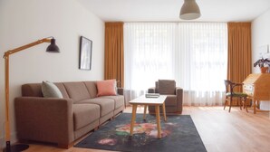 Un salon comprenant un canapé, un fauteuil, une table basse et un bureau avec une chaise.