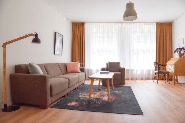 A living room with a sofa, armchair, coffee table, and a desk with a chair. - Beautiful first and second floor apartment in historic Leiden (Leiden)