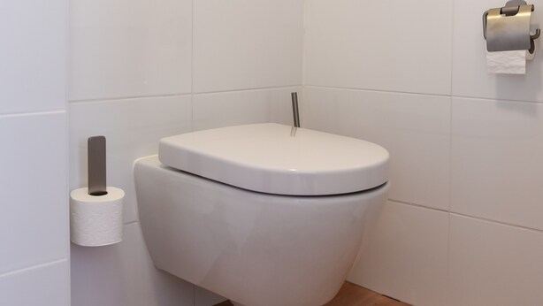 Un baño moderno con un inodoro blanco, un dispensador de papel higiénico y un dispensador de toallas de papel en la pared.
