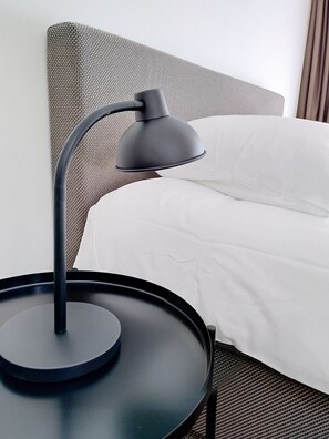 A bed with white bedding, a black table with a lamp, and a woven headboard. - Beautiful first and second floor apartment in historic Leiden (Leiden)