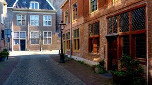 Une rue pavée bordée de bâtiments historiques, un lampadaire et des plantes en pot.