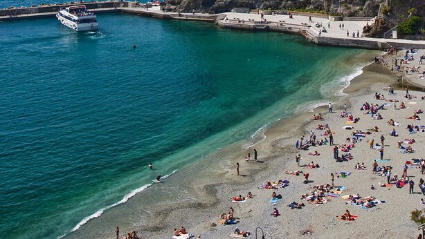 A coastal town with a beach, a boat in the water, and a castle-like building on a cliff. - Large Apartment in a splendid quiet area - seaview (Italia)