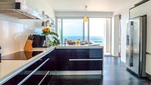 A modern kitchen with a large island, stainless steel appliances, and a view of the sea. - Villa Chimera by LovelyStay (Caniço)