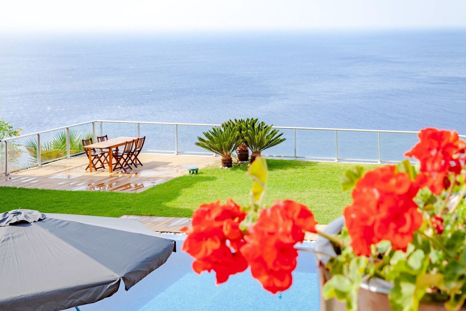 A patio with a table and chairs overlooking the sea.