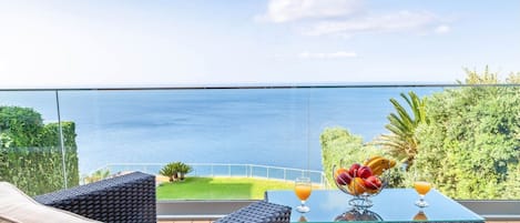 A balcony with wicker furniture, a glass table, and a fruit bowl.