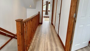 A hallway with wooden flooring, white walls, and a wooden railing. - 3 Sheraton Apartments, Modern Luxury Apartment,Breathtaking Views of Ben Nevis (Fort William)