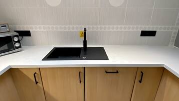 A modern kitchen with a white countertop, wooden cabinets, and a black sink.