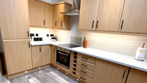 A modern kitchen with wooden cabinets, a built-in oven, and a skylight. - 3 Sheraton Apartments, Modern Luxury Apartment,Breathtaking Views of Ben Nevis (Fort William)