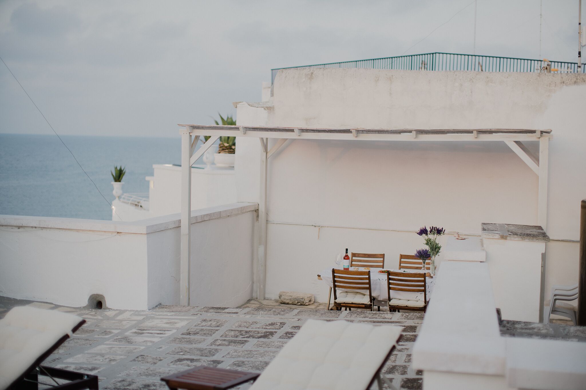 A terrace with a view of the sea, white walls, and a table with chairs.