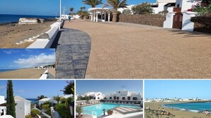 A coastal hotel with a paved walkway leading to the beach, a pool area, and white buildings with balconies.
