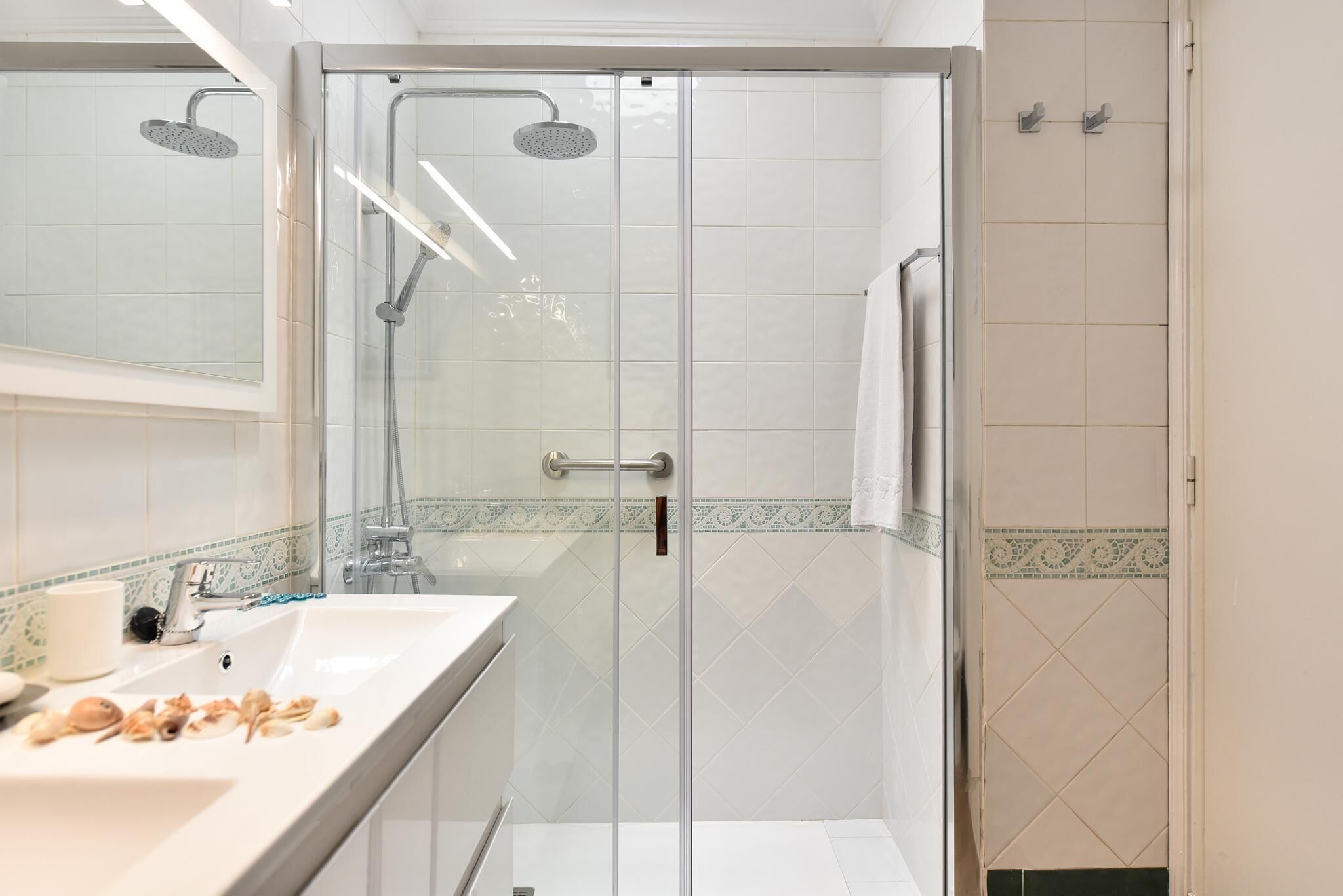 A modern bathroom with a glass-enclosed shower, a white sink, and a mirror.