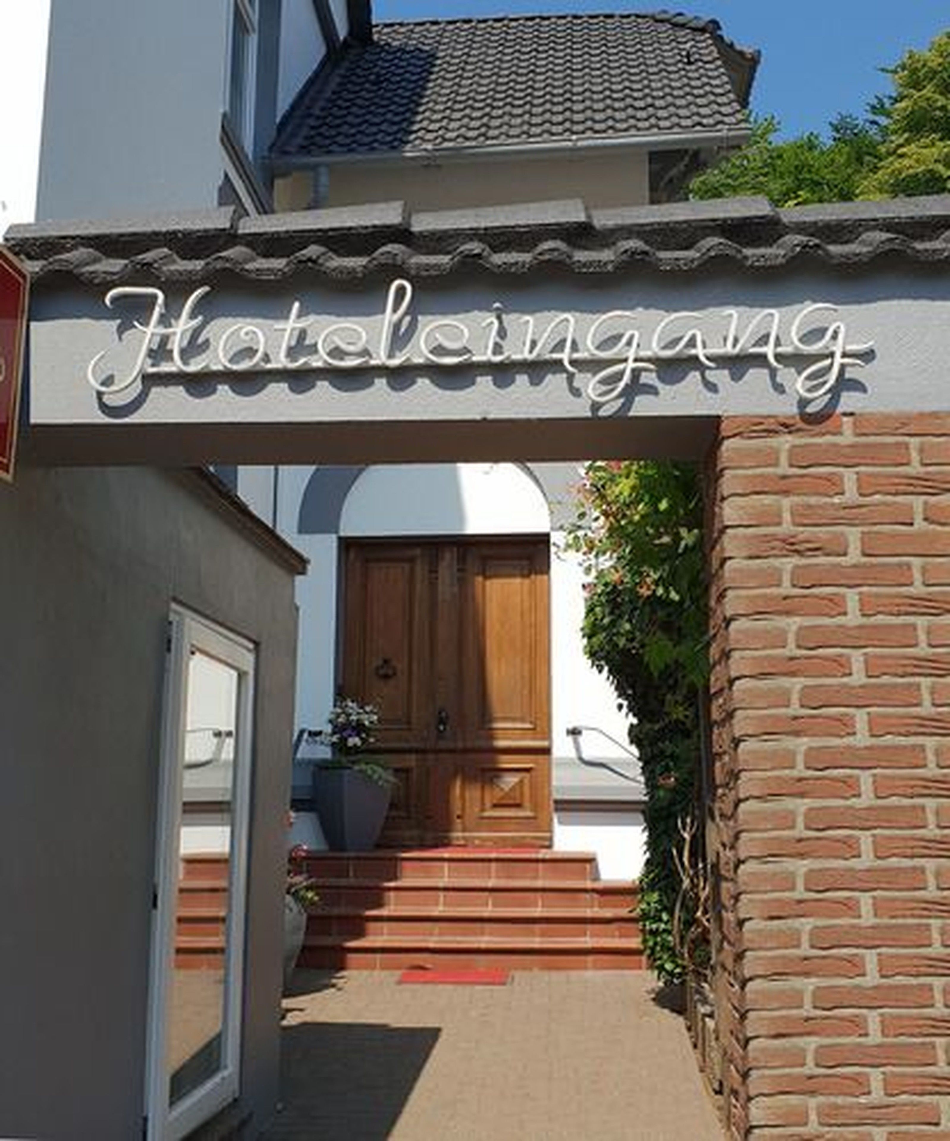 A hotel entrance with a sign reading "Hoteleingang" and a wooden door.