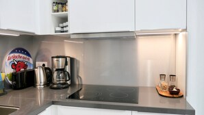A modern kitchen with a coffee maker, a kettle, and a stove. There is a shelf with spices and a decorative plate with a bull design. - CENTRAL = BEAUTIFUL Area ; MODERN BRIGHT Apartment (Paris)