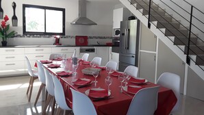 Una cocina moderna con armarios blancos, una campana extractora de acero inoxidable y un refrigerador DELICE rojo.