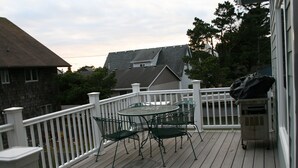 A wooden deck with a white railing, a round table, and four chairs. - Bright, sunny house w/hot tub, close to beach! (Seaside)