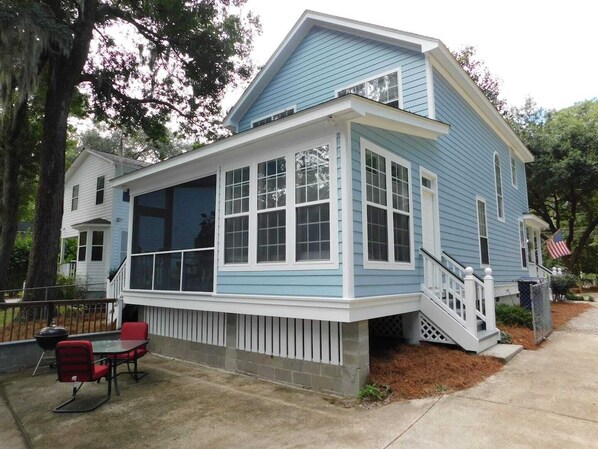 A two-story house with a covered porch, a small outdoor seating area, and a flag.