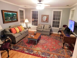 A living room with two sofas, a coffee table, a TV, and a patterned rug.