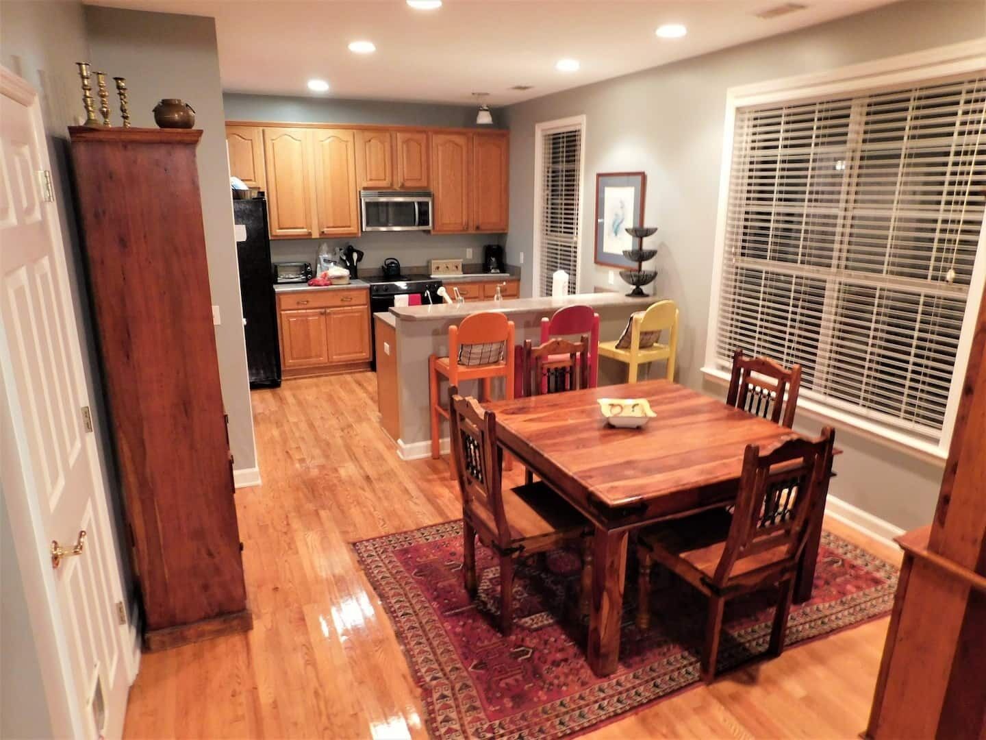A kitchen with wooden cabinets, a microwave, and a dining area with a table and chairs.