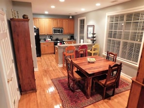 A kitchen with wooden cabinets, a microwave, and a dining area with a table and chairs.