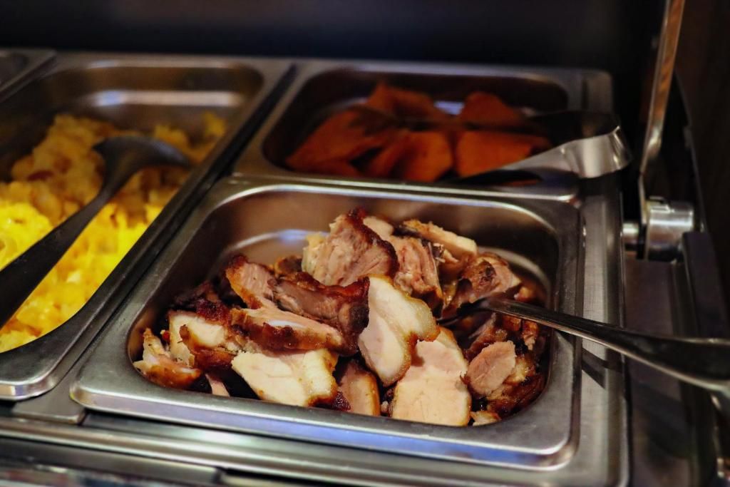 A buffet with various food items including sliced meat, potatoes, and a yellow dish.