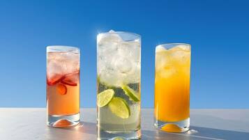 Tres vasos de bebidas con cubitos de hielo y rodajas de lima.