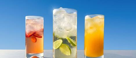 Three glasses of beverages with ice cubes and lime slices.