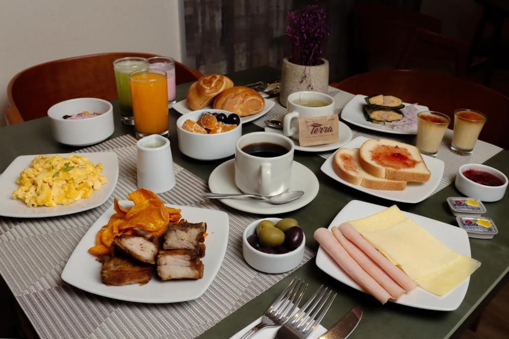 A breakfast table with plates of food, drinks, and condiments.