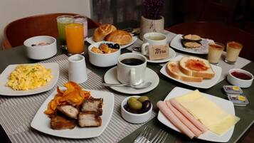 A breakfast table with plates of food, drinks, and condiments.