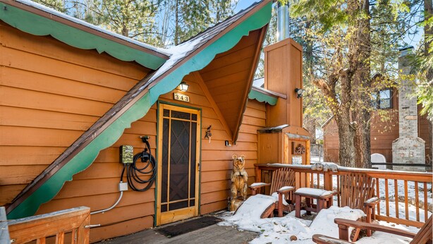 A wooden cabin with a porch, outdoor seating, and a bear statue.