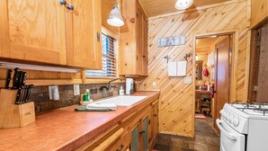 A wooden kitchen with a sink, stove, and cabinets.
