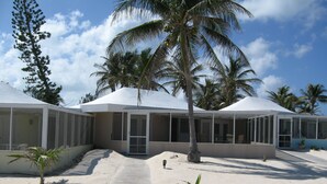 A resort with covered structures, a concrete pathway, and palm trees. - Sea Paradise # 24 (Cayman Islands)