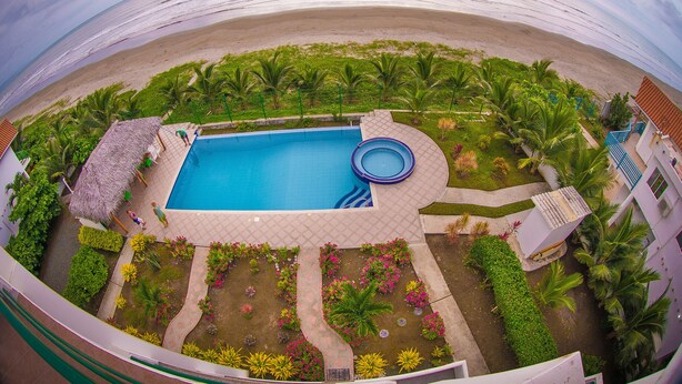 Piscina rodeada de plantas tropicales y vista a la playa.