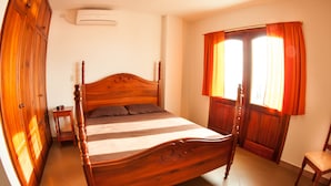 Una cama con dosel de madera, un cabecero, una mesita de noche y una silla.
