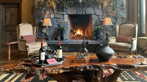 A cozy room with a stone fireplace, two chairs, a wooden coffee table, and a decorative mantle. - One Of A Kind Mountain Home With Gorgeous  mountain Views  (Canmore)